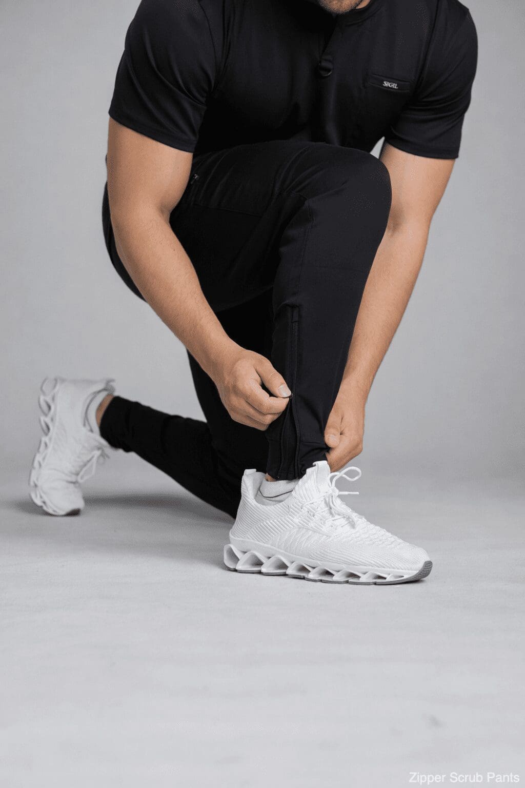 Man kneeling adjusting black zippered joggers