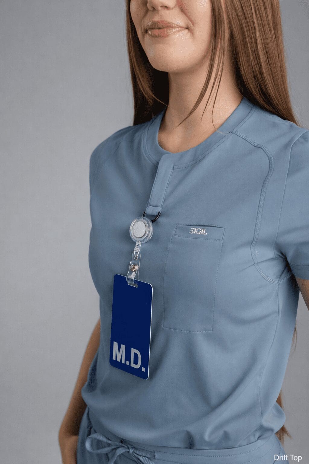 Female doctor wearing cyan scrub top with badge